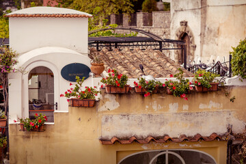 A beautiful old house with flowers and a tiled roof on a mountainside in Positano. Italian architecture.