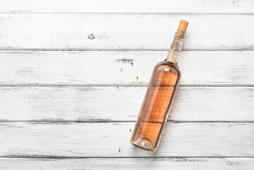 Bottle of rose wine flat lay on a white wooden background. View from above.