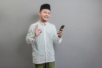 Asian Muslim man standing with crossed arm isolated on a gray background