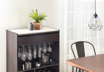 A Cozy Dining Nook with a Corner of a Sleek Wooden Table and a Bar Cabinet Displaying an Array of...