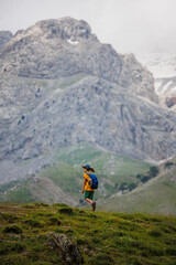 Fototapeta premium boy with a backpack on a hike against the backdrop of the mountains. child traveler with backpack, hiking, travel, mountains in the background, kids summer vacation.