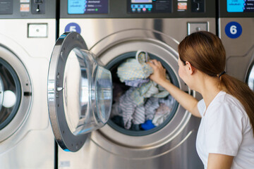 Asian female housewife bring used clothes to wash at self-service laundry shop. - obrazy, fototapety, plakaty