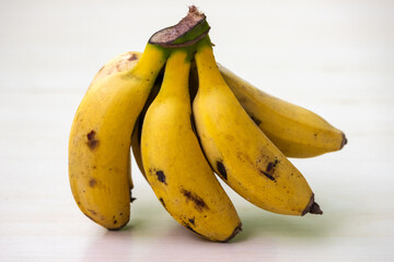 A bunch of yellow bananas on an off-white background. Bananas are healthy fruit, they can be a good source of nutrients.