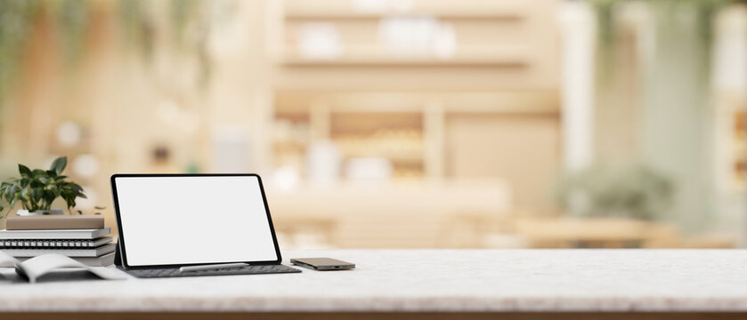 A digital tablet white-screen mockup with a wireless keyboard on a table in a cosy coffee shop.