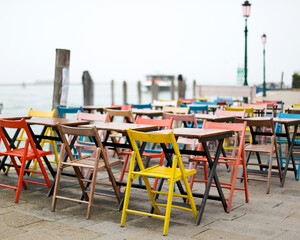 Fototapeta na wymiar Vibrant tables and chairs set by the waterfront.