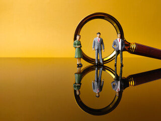 Miniature people and magnifying glass with reflection on a yellow background