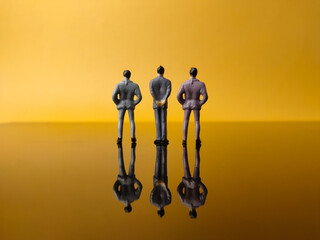 Three men miniature people with reflection on a yellow background