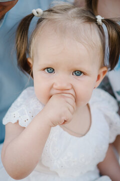 Little cute beautiful girl is eating. The daughter sits in her mother's arms. Funny face of a child closeup.
