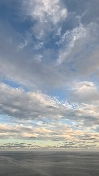 Timelapse fluffy Cumulus clouds moving in bright sunset sky. Abstract aerial nature summer ocean sunset, sea and sky view. Vacation, travel, holiday concept. Weather and Climate Change. Vertical video