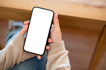 A close-up shot of a woman using her smartphone at a table indoors.