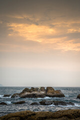 Sunset burning the clouds into orange, on the rocks and waves near the coastline, in Keelung, Taiwan.
