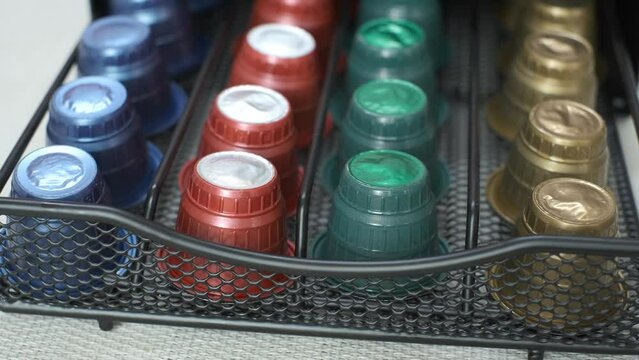 Female hand opens a box with multi-colored capsules for coffee machine, close-up.