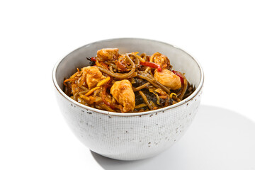 Asian fried buckwheat noodles with chicken and vegetables isolated on white background. Japanese fried noodles teriyaki in ceramic bowl. Fried on wok soba with chicken in minimal style. Wok menu.