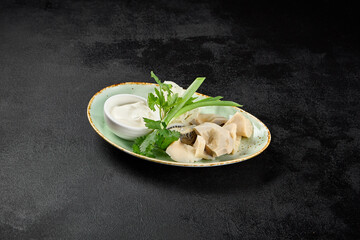 Russian appetizer from salted milk mushrooms with sour cream and onion on dark concrete background. Salted gruzdi in minimal style on black table. Mushroom appetizer on plate. Milk mushrooms.
