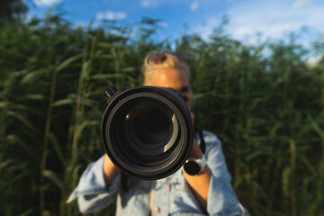 Fototapeta premium Girl photographer outdoors with a camera with a super zoom lens.