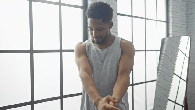 African american man scratching arm indoors near window with natural light