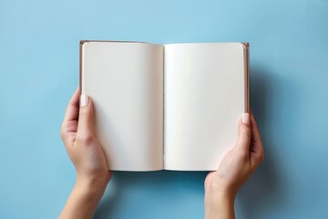 Close-up of hands holding an open, blank notebook against background