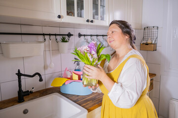 mature woman holding spring bouquet of white and purple hyacinths in hands while wearing yellow...