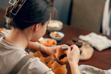 A young woman makes indentations in cupcakes for filling. the concept of baking at home in the...