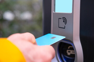 close-up man holding bank card to pay for charging station, electric vehicle charger factory,...