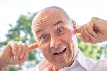 senior, funny man 65 years old holds to ear, male face, facial expression, auditory hallucinations,...