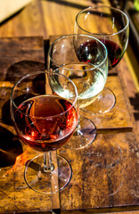 Three glasses with three different wines on a wooden table.