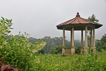 A picturesque gazebo stands gracefully amidst a vast field, exuding tranquility and charm.