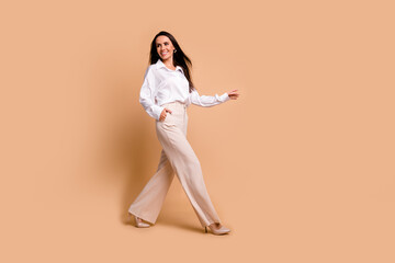 Full length photo of positive dreamy woman wear white shirt carefree walking empty space isolated...