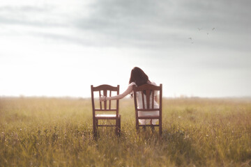 sad woman looks nostalgically at her lover's empty chair  in the middle of nature