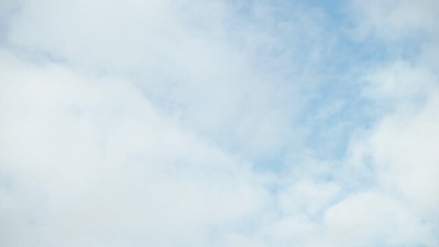 Slowly moving delicate white clouds against the blue sky.