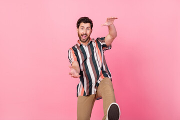 Photo of mature age positive man in striped shirt hands towards him dancing having fun discotheque isolated on pink color background