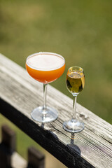 orange cocktail and champagne glass on wooden rail summer cafe