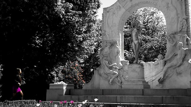 Beautiful Asian woman in purle clothes visiting Johann Strauss monument in black and white coloring, slowmotion, wide shot. Vienna.