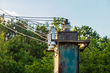 Old high voltage transformer with insulators and wires outdoors