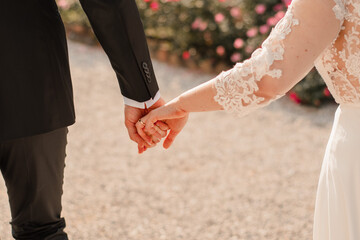 A portrait of a bride and groom holding hands on their wedding day in a natural background.