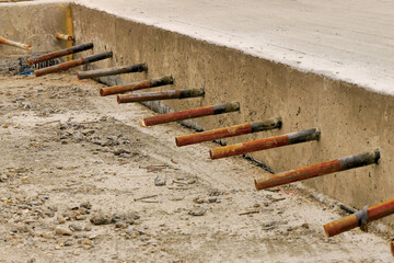 concrete slab edge showing steel dowel bars in a row.