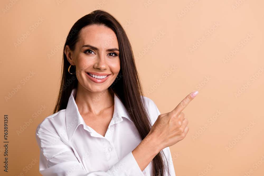 Poster Photo of cheerful lovely lady toothy smile indicate finger empty space novelty isolated on beige color background