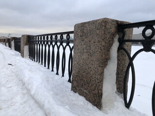 winter, granite pillar and cast iron embankment fence in the snow, landscape St. Petersburg