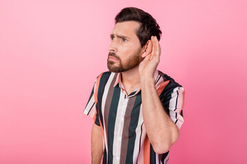 Photo of focused concentrated young man hand near ear listen eavesdrop empty space isolated on pink...