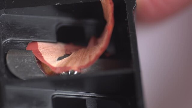 Nude beige cosmetic pencil rotates in dual makeup pencil sharpener, macro. Sharpening lip pencil with sharpener tool