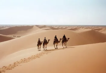Selbstklebende Fototapeten A caravan of camels led by a person in desert  © Uzzi1001