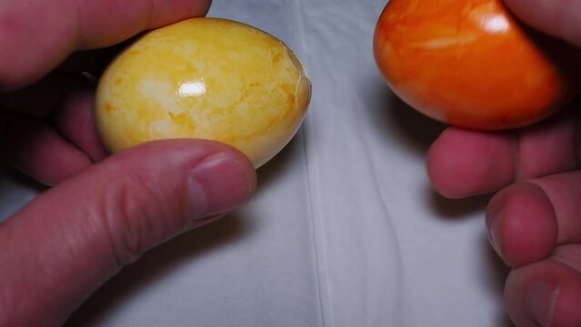 Person hitting colored Easter eggs each other. breaking egg shell, slow motion Close up 