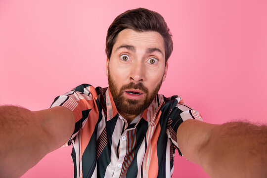 Selfie photo of young astonished brunet man mature age blogger speechless staring looking into camera isolated on pink color background