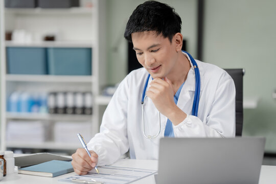 Portrait of Asian middle age male doctor in white lab coat and stethoscope while consult online in laptop via video conference. advice on good mental health management and medical treatment costs.