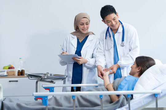 Two conficent doctor or specialist of kidney cancer talking together with female mix race patient on bed at medical ward, checkup, recovering after successful surgery concept.