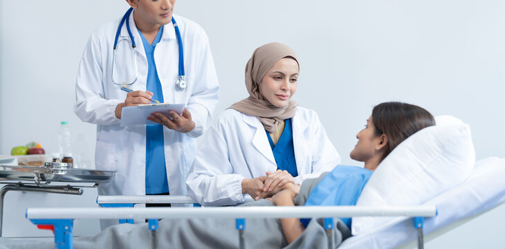 Two conficent doctor or specialist of kidney cancer talking together with female mix race patient on bed at medical ward, checkup, recovering after successful surgery concept.