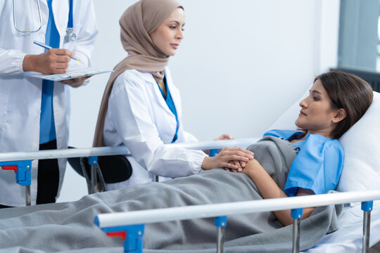 Two conficent doctor or specialist of kidney cancer talking together with female mix race patient on bed at medical ward, checkup, recovering after successful surgery concept.