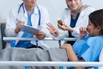 Two conficent doctor or specialist of kidney cancer talking together with female mix race patient on bed at medical ward, checkup, recovering after successful surgery concept.