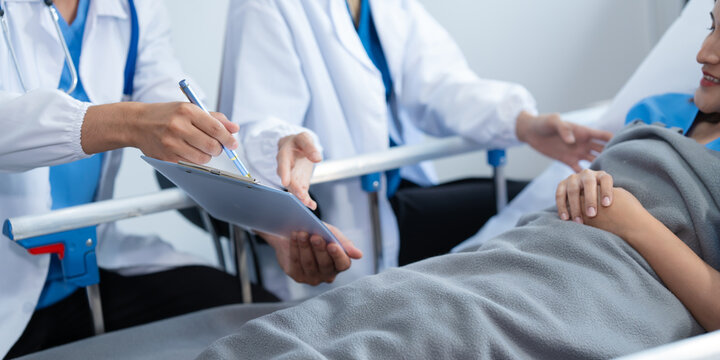 Two conficent doctor or specialist of kidney cancer talking together with female mix race patient on bed at medical ward, checkup, recovering after successful surgery concept.