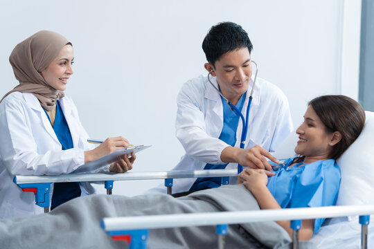 Two conficent doctor or specialist of kidney cancer talking together with female mix race patient on bed at medical ward, checkup, recovering after successful surgery concept.